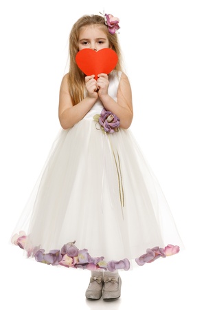 Adorable 6 years old girl in princess dress holding heart shape, over white backgroundの写真素材