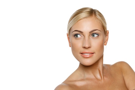 Closeup portrait of a beautiful blond female model on white background looking to the side at blank copy spaceの写真素材