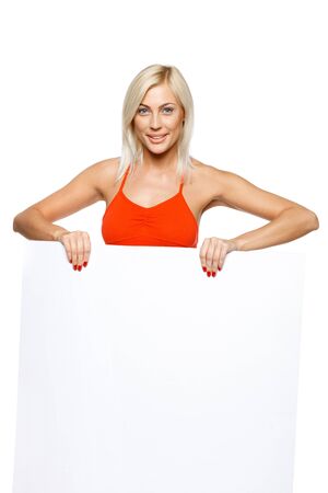 Smiling woman standing behind and holding a white blank billboard   placard, over white backgroundの写真素材
