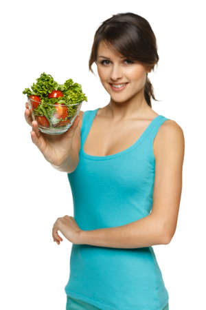 Smiling woman offering you a bowl with salad, shallow depth of field, focus on the salad, over whiteの写真素材