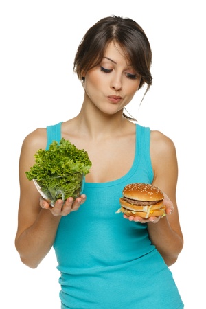 Hesitating woman making decision between healthy salad and fast food, over white backgroundの写真素材
