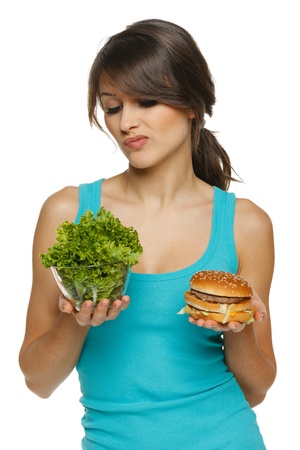 Hesitating woman making decision between healthy salad and fast food, over white backgroundの写真素材