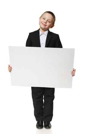 Full length of a schoolboy in black suit holding blank placard   banner, over white backgroundの写真素材