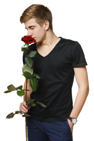 Young handsome man smelling the red rose with closed eyes, over white backgroundの写真素材