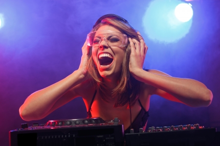 Excited DJ girl on decks on the partyの写真素材