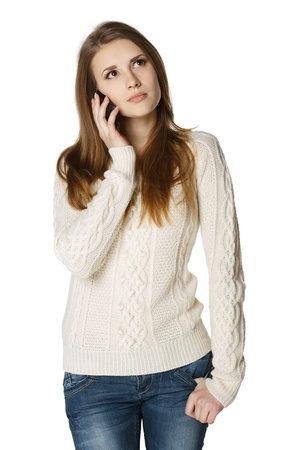Pensive young woman talking on cell phone looking up, over white backgroundの写真素材