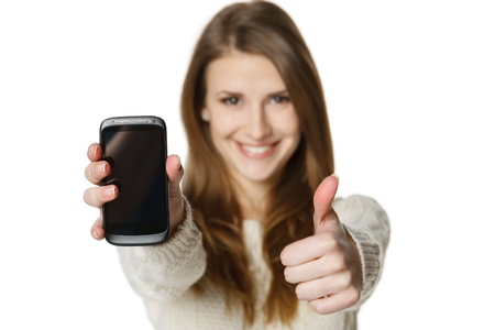 Closeup of happy young woman showing her mobile phone and gesturing thumb up sign  Shallow depth of...