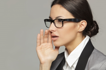 Side view portrait of business woman  calling out to someone over grey backgroundの写真素材