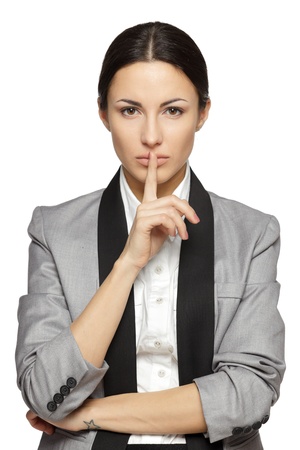 Businesswoman with finger on lips over grey backgroundの写真素材