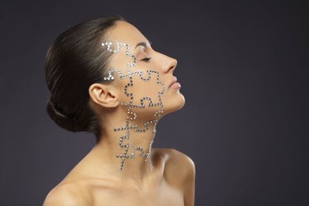 Side view portrait of female with beauty crystal puzzle on her faceの写真素材