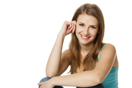 Portrait of a pretty young woman sitting in front of a white backgroundの写真素材