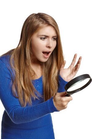 Surprised woman looking through the magnifying glass, over white background の写真素材
