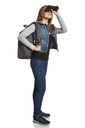 Hiking  Girl hiker with backpack looking through binoculars in full lengthの写真素材