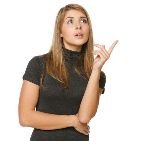 Closeup portrait of pretty female pointing upwards at copyspace over white backgroundの写真素材