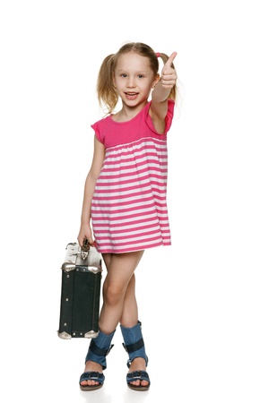 Little tourist  Little girl with old fashioned suitcase showing thumb up signの写真素材