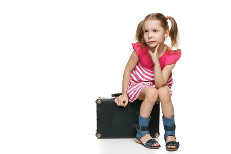 Little tourist  Little girl with sitting on the old fashioned suitcase in full length looking away at blank space for your text, over white backgroundの写真素材