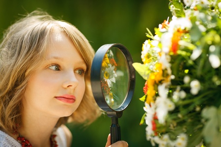 Girl exploring flowers through the magnifying glass outdoorsの写真素材