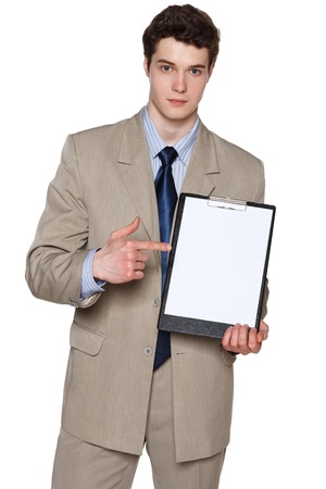 Young serious businessman holding blank whiteboard, pointing at it, over white backgroundの写真素材