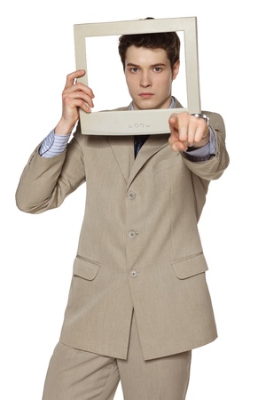 Serious young businessman looking at you through the monitor screen and pointing at you, against white backgroundの写真素材