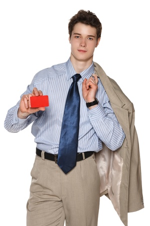 Smiling young business man with suit over shoulder holding blank credit card, against white backgroundの写真素材