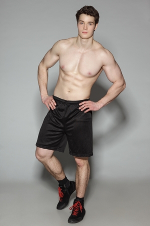 Athletic young man shirtless standing in full length, over gray backgroundの写真素材