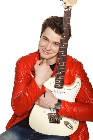 Young man feeling happy while embracing his white electric guitar, over white backgroundの写真素材