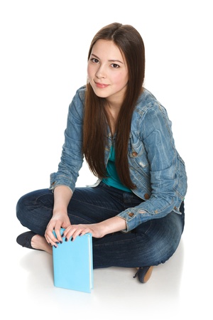 Young smiling relaxed female student sitting on floor with a book, isolated on whiteの写真素材