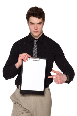 Young businessman holding blank clipboard , pointing at it, looking at camera with severe glance, over white backgroundの写真素材