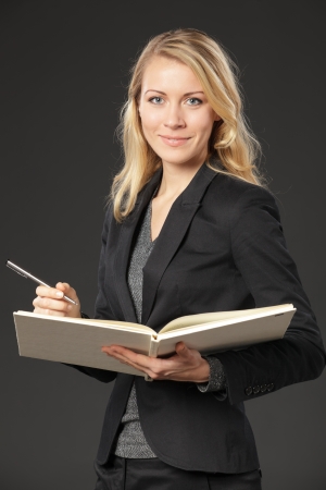 Young female standing with the opened book and a pen, isolated on white backgroundの写真素材