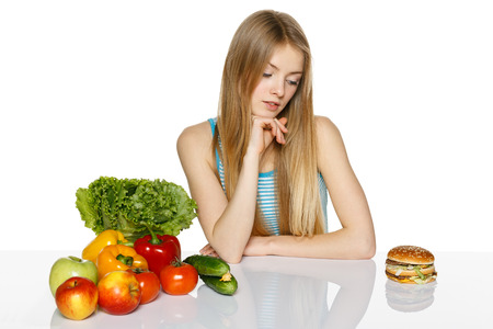 Woman making decision between healthy food and fast food, over white backgroundの写真素材