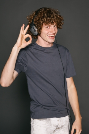Happy male in headphones gesturing OK sign, against gray backgroundの写真素材