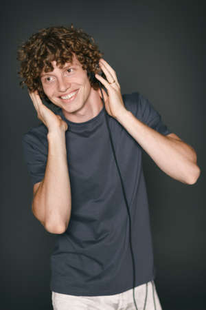 Smiling redheaded man in casual clothes with headphones looking out of frameの写真素材