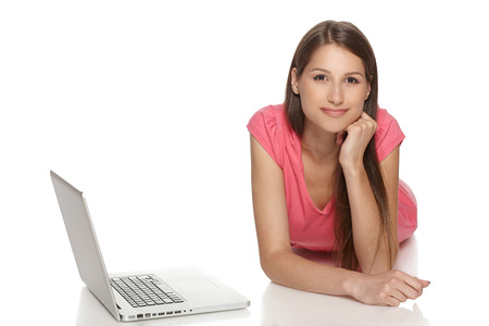Smiling woman with laptop lying on the floor, isolated over a white backgroundの写真素材