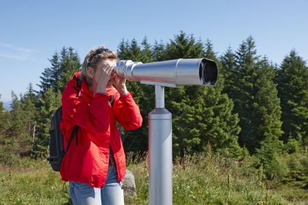 Woman looking through sightseeing binoculars の写真素材