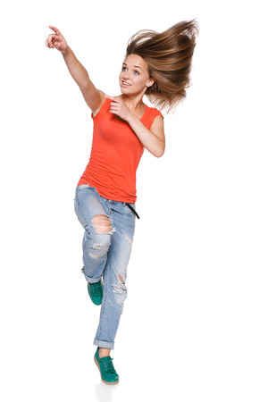 Jumping girl pointing to the side over white の写真素材