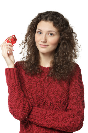 Young female in sweater holding small red gift box isolated on white backgroundの写真素材