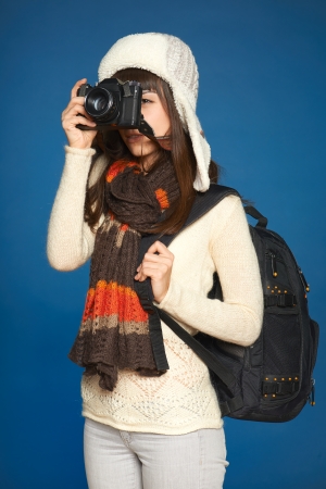 Winter girl looking through the photocamera viewfinder over blue backgroundの写真素材