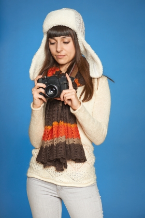 Woman photographer adjusting photo camera settings over blue の写真素材