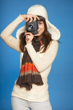 Woman photographer looking through the photo camera viewfinder at you, over blue の写真素材