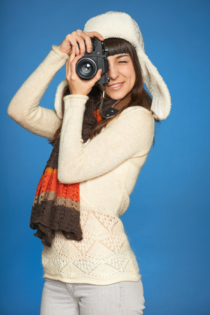 Woman photographer looking through the photo camera viewfinder at you, over blue の写真素材