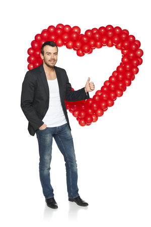 Love concept. Full length dude man standing with heart shape formed of balloons gesturing thumb up, isolated on white .の写真素材