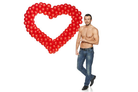 Love concept. Full length handsome shirtless man showing heart shape formed of balloons, isolated on white .の写真素材