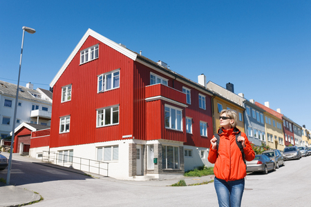 Woman tourist standing against bright multicolored wooden houses, Kristiansund, Norwayの写真素材
