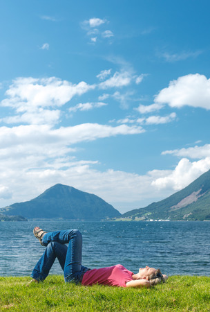 Woman relaxing enjoying at the fjord coast in a summer sunny day, Norwayの写真素材