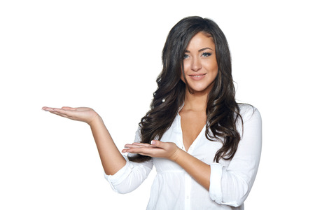 Funky and stylish young woman in jeans and white shirt holding blank copy space on her open palm, over white backgroundの写真素材