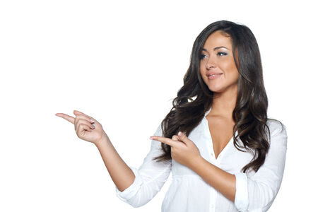 Stylish young woman in white shirt holding blank copy space and pointing at it, on her open palm, over white backgroundの写真素材