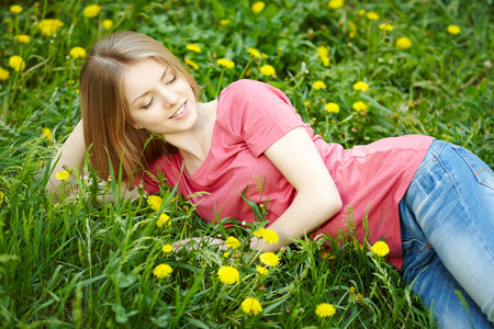 Spring girl lying on the field of dandelionsの写真素材