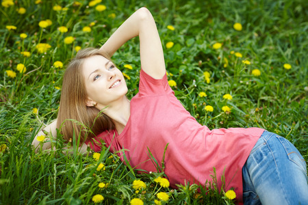 Spring girl lying on the field of dandelionsの写真素材