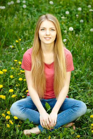 Female sitting on the field of dandelions looking upの写真素材