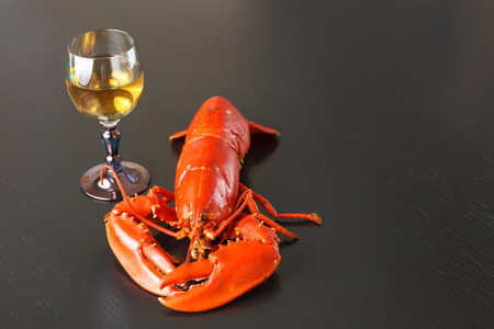 Boiled Atlantic Lobster with glass of white wine on dark wooden table.の写真素材